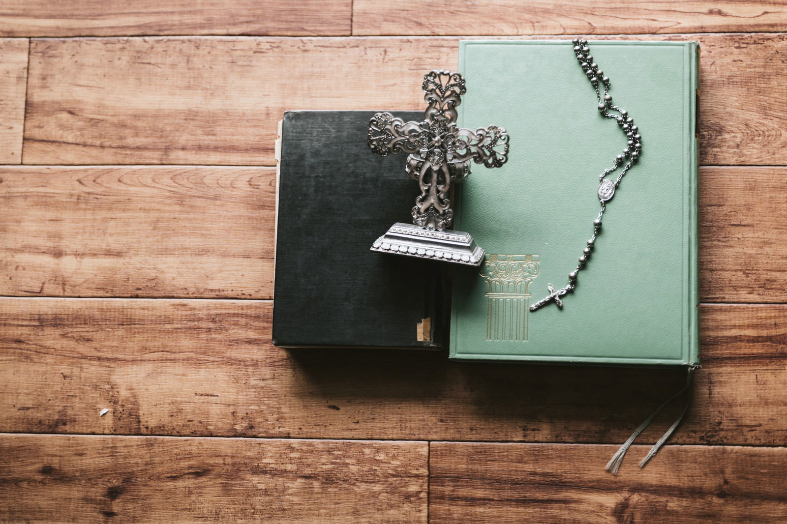 木製テーブルの上に置かれた開かれた聖書とロザリオと燭台