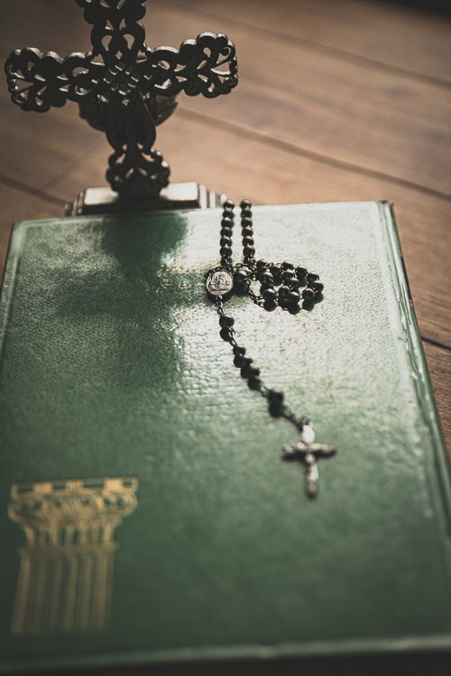 緑色の表紙の聖書に置かれたロザリオのチャーム