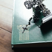 自然光が差し込む中のロザリオと十字架の燭台、古書の写真