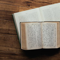 木製テーブルに無造作に置かれた聖書と古書の写真