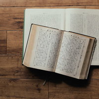 木製テーブルに開かれたままの聖書と古書の質感の写真