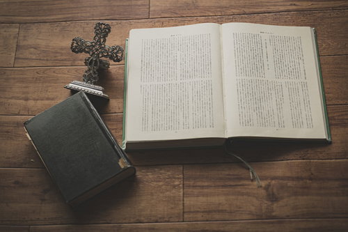 木製テーブルに無造作に置かれた十字架の燭台と聖書