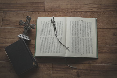 開いた聖書の上に置かれたロザリオと十字架
