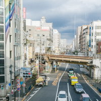 西日暮里駅前の高架橋と市街地の交差点を行き交う車両の写真