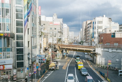 西日暮里駅前の高架橋と市街地の交差点を行き交う車両