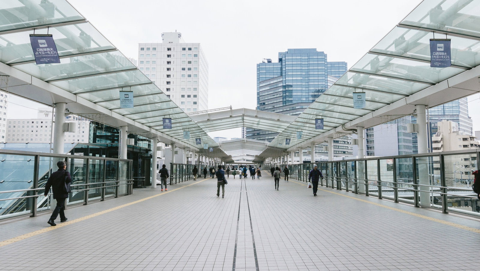 大崎駅西口のガラス屋根通路を歩く人々