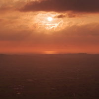 夕暮れに染まる雲間から見える太陽、南砺市の散居村上空の写真