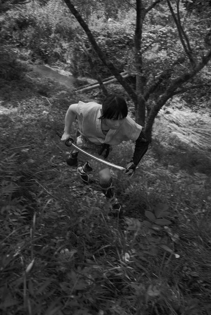 林の中を刀を握って逃げ場を求めて走る山賊の男性［モデル：まーこ］