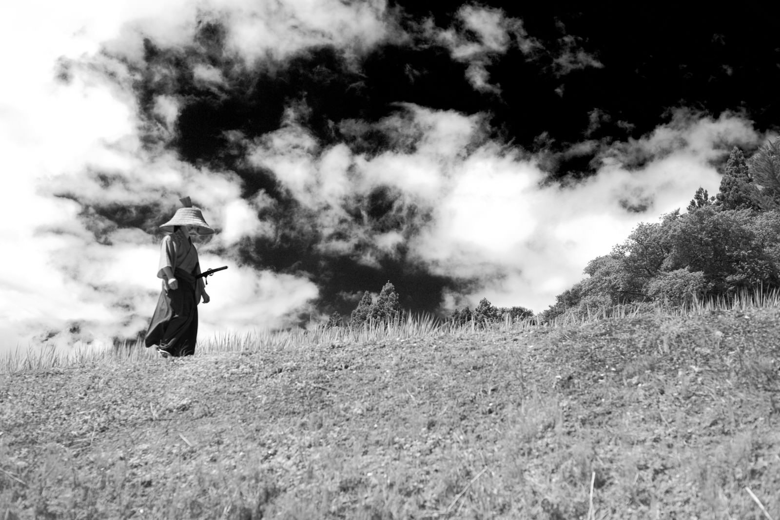 笠と袴姿の侍が丘を歩くモノクロ写真［モデル：まーこ］