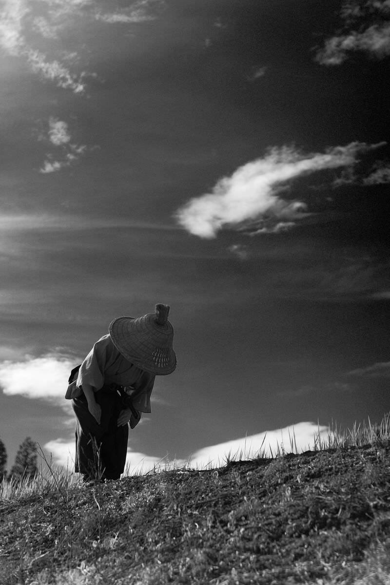 笠をかぶった袴姿の侍が深々と頭を下げてお辞儀をしている様子［モデル：まーこ］