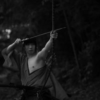 袴姿で片腕を出して大弓を引く侍の武道動作の写真