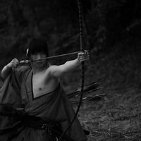 袴姿で大弓を引く男性の弓道の姿勢と集中力の写真