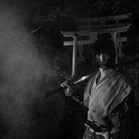 煙を纏う日本刀を担ぐ侍と鳥居の写真