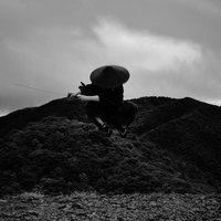 御霊櫃峠の岩上で飛翔する袴姿の侍の一閃と刀の写真