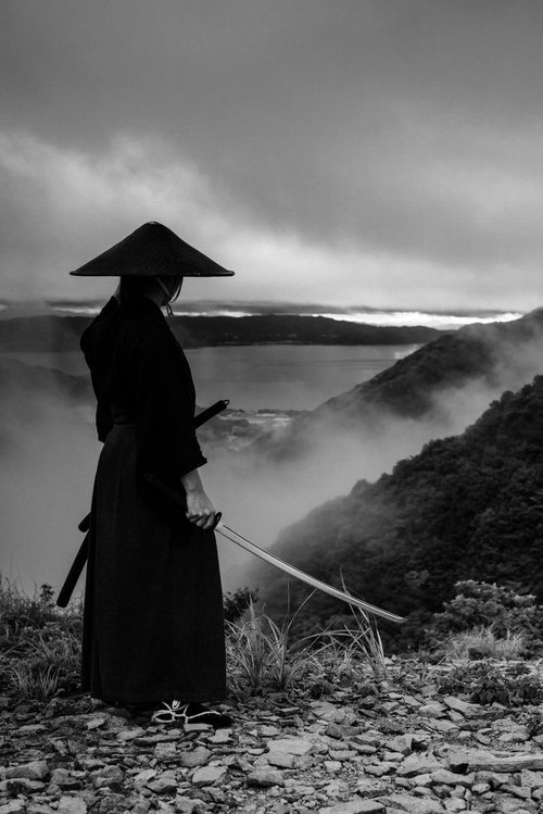 御霊櫃峠から遠くを眺める網代笠の侍の後ろ姿