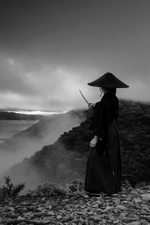 目指す方向に刀を翳す袴姿の侍の後ろ姿