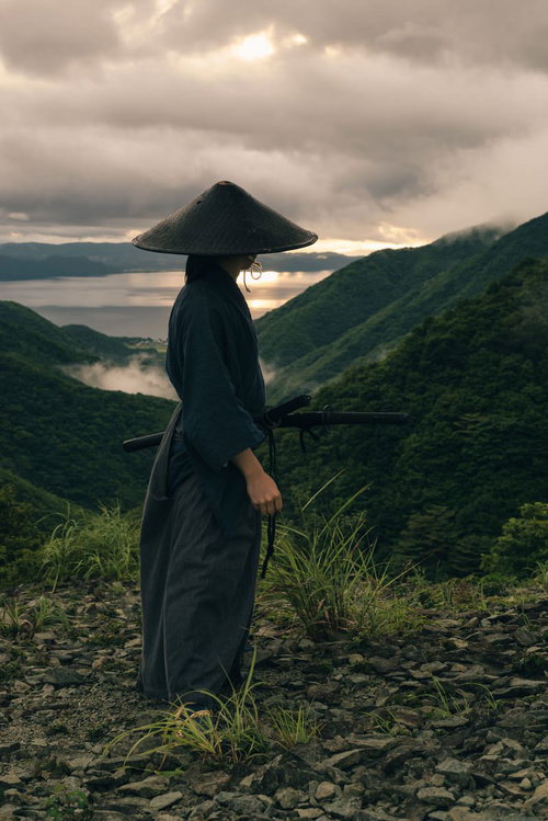 福島県郡山市の御霊櫃峠で夕日を眺める侍が厚い雲に包まれた峠の風景
