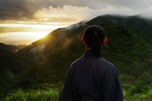 御霊櫃峠から夕日を眺める袴姿の侍のシルエット