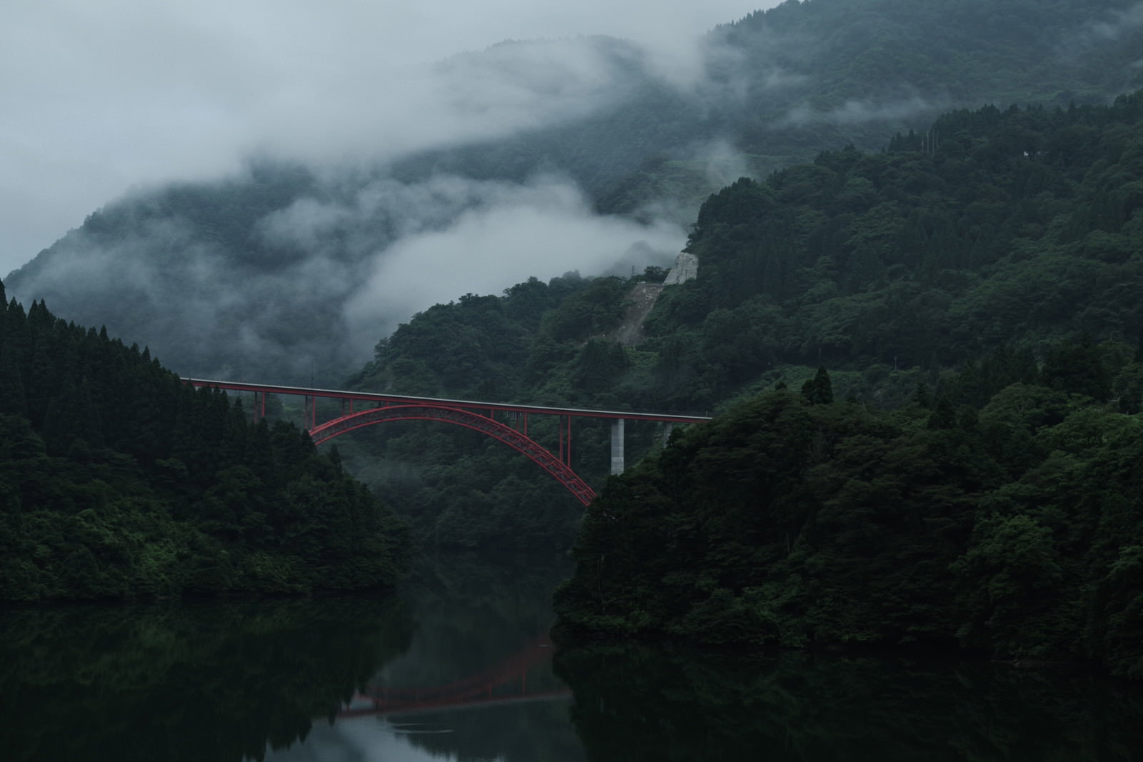 霧の庄川峡に架かる赤いアーチ橋
