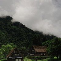 沸き立つ雲と山間の南砺市相倉集落の合掌造りの写真
