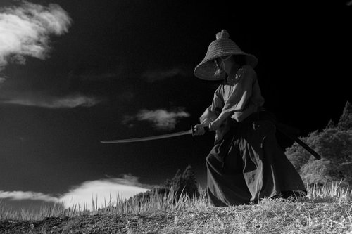 刀を相手に向け立ち合い中の笠を被った侍の用心棒