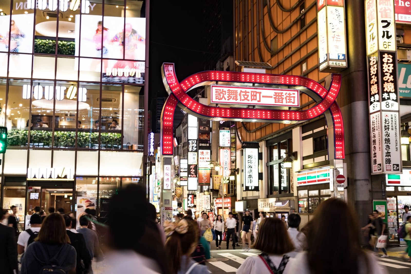 夜の歌舞伎町一番街を歩く大勢の人々とネオンサインが光る繁華街の風景