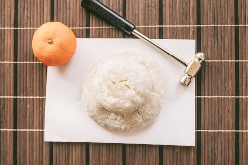 鏡開きの準備、みかんと金槌で乾いた鏡餅を割る