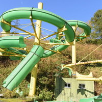 廃墟となったプール施設の折れたウォータースライダーの写真