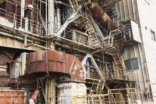 使われていない工場廃墟の金属配管と階段、錆びた産業遺産