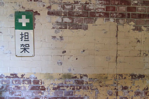 「担架」と書かれた古い廃墟の壁に記された緑色の十字マーク