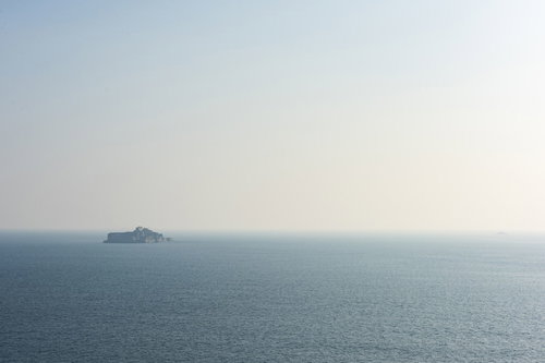 海の向こうに水平線上に浮かぶ軍艦島の廃墟