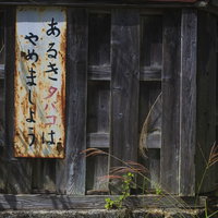 古い木造建物に設置された「あるきタバコはやめましょう」の注意看板の写真
