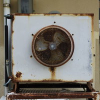 かなり古い室外機と錆びた外壁、劣化した建物の廃墟の写真