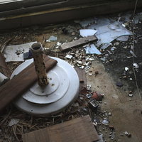 割れたガラスやゴミが散らばる廃墟の床に積もる土埃の写真