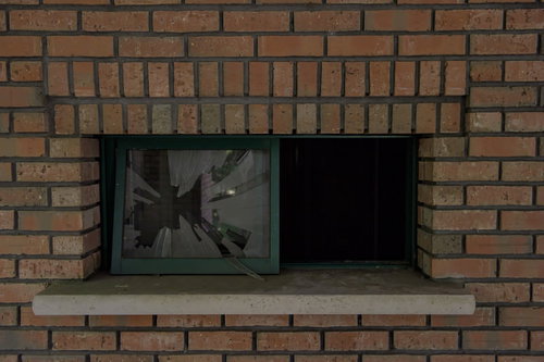 レンガの壁に割れたガラス窓の室内風景