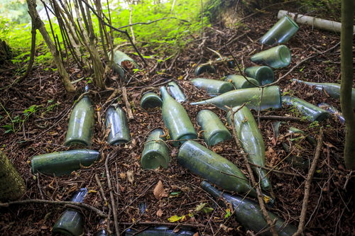 山奥に捨てられた複数の瓶と廃棄物による環境破壊
