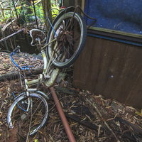 廃墟に放置された錆びたパンク自転車と朽ちた残骸の写真