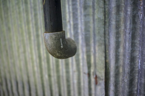 古いトタン壁に取り付けられた黒い排水管と経年劣化