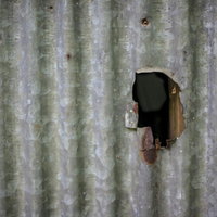 穴の空いたトタン壁面の写真
