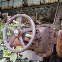 廃墟の配管に取り付いた錆びついたバルブの風景の写真