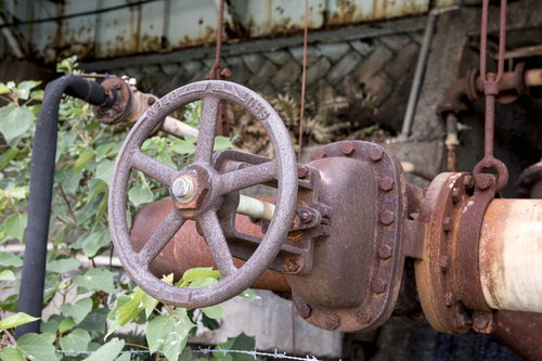 廃墟の配管に取り付いた錆びついたバルブの風景