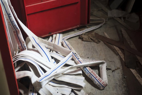 白い消防ホースが床に散らばる廃墟の屋内空間