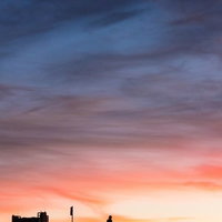 土手を走る自転車の夕焼けシルエット、夕暮れの風景の写真