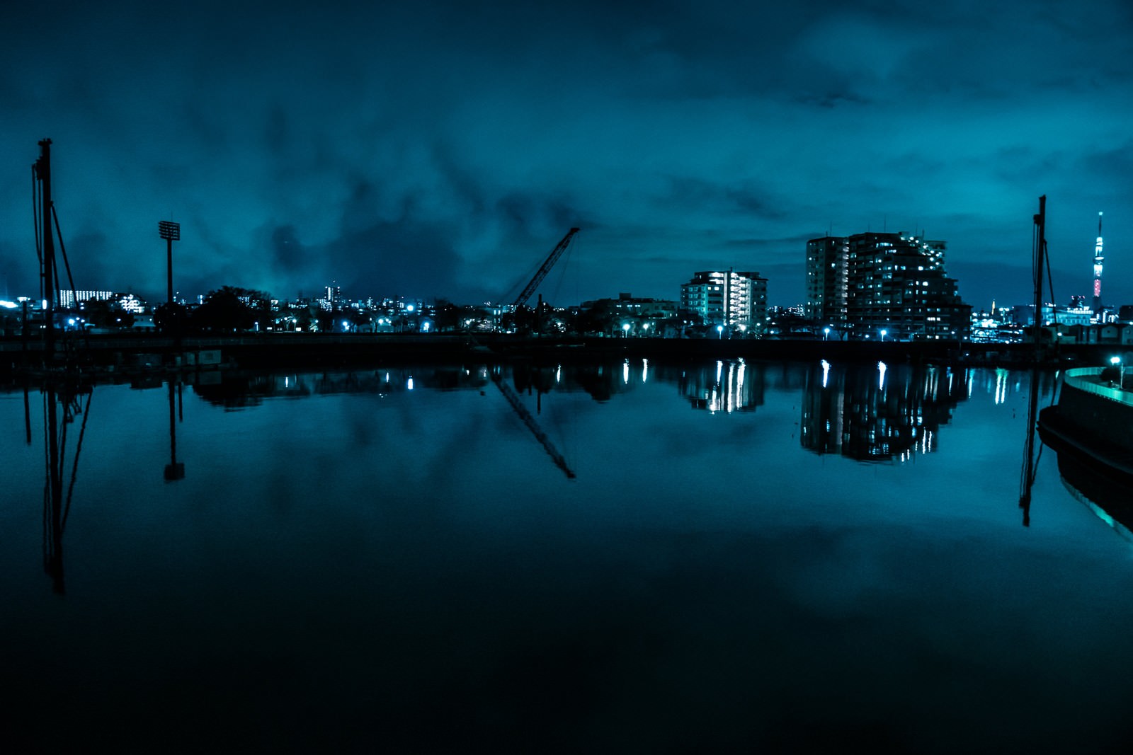 静かな湖面に工業地帯の夜景が反射している風景