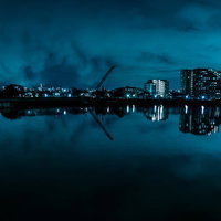 湖面に映る街並みとクレーン、工業地帯の夜景の写真