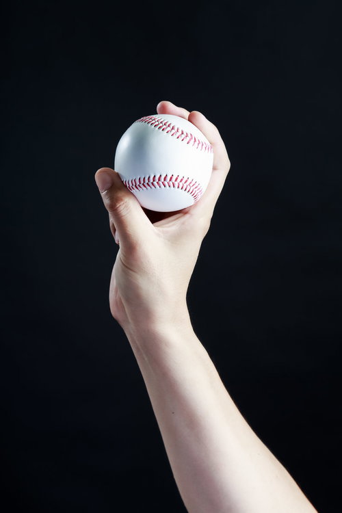 カーブ（変化球）の握り方を示す投手の手と白いベースボール