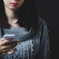しつこい勧誘メールに飽き飽きしてスマホを見る女性の写真