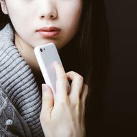 スマホを顎にあてて考える憂鬱な女性のポートレートの写真