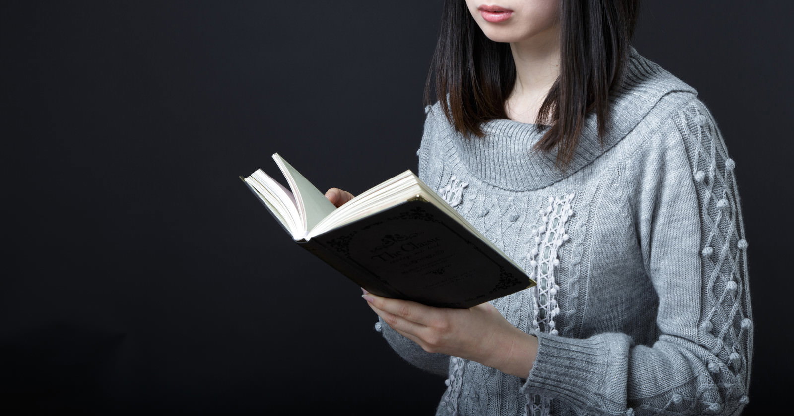 暗闇の中でニットを着て本を読む女性