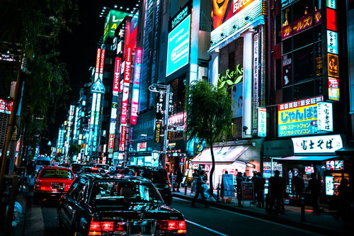 新橋の繁華街のネオンと路肩に停めるタクシー